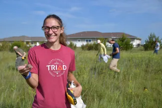 Woman holds a texas horned lizard in a field.