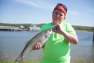 Cooper Walker holding a striped bass caught from Lake Texoma.