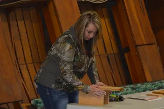 A woman frames the pieces of a wooden nest box. 