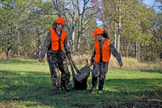 A mother and daughter bring in their harvested deer.