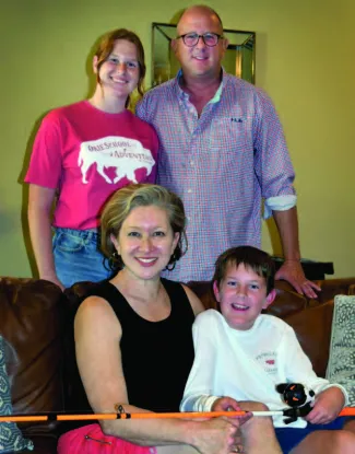 A family with dad and daughter standing and mother and son sitting. 