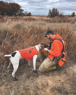 man in orange jacket with dog in orange jacket