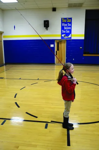 A girl holding a spincast rod/reel. 