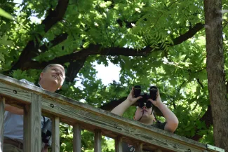 A boy and man look through binoculars on an elevated walkway. 