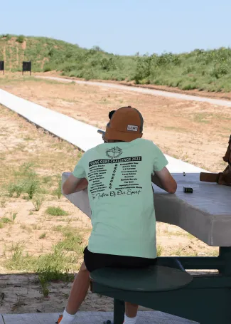 A person is aiming their rifle down a WMA shooting range.