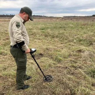 Investigator Kody Moore looks for a spent shell casing that was evidence in an illegal deer case.