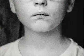 A black and white photo of a child's face from the nose down.