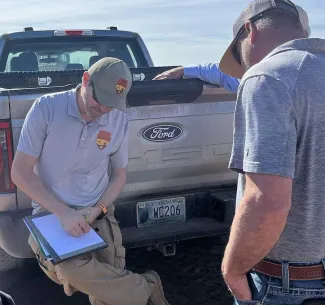 An ODWC biologist takes notes on his clipboard while talking to a landowner.