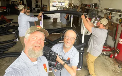 Two of Outdoor Oklahoma's video crew team members taking a selfie with their equipment and some ODWC employees that are working on a fish habitat project