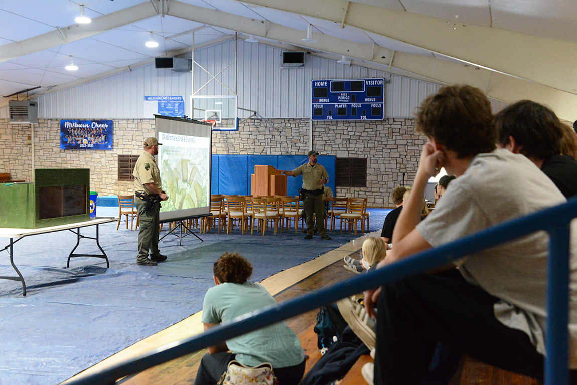 A game warden giving a presentation to a group of students in a gymnasium