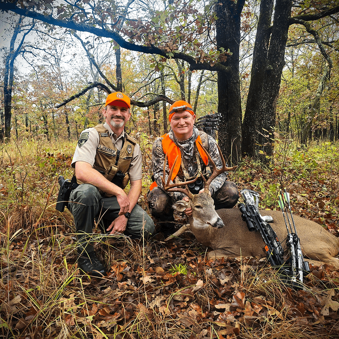 A game warden with a hunter and harvested deer in the field